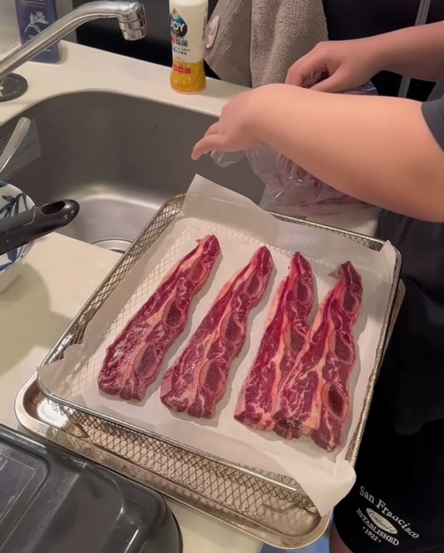 Gros plan montrant des mains utilisant du papier absorbant pour presser les côtelettes de bœuf afin dabsorber lhumidité de surface.