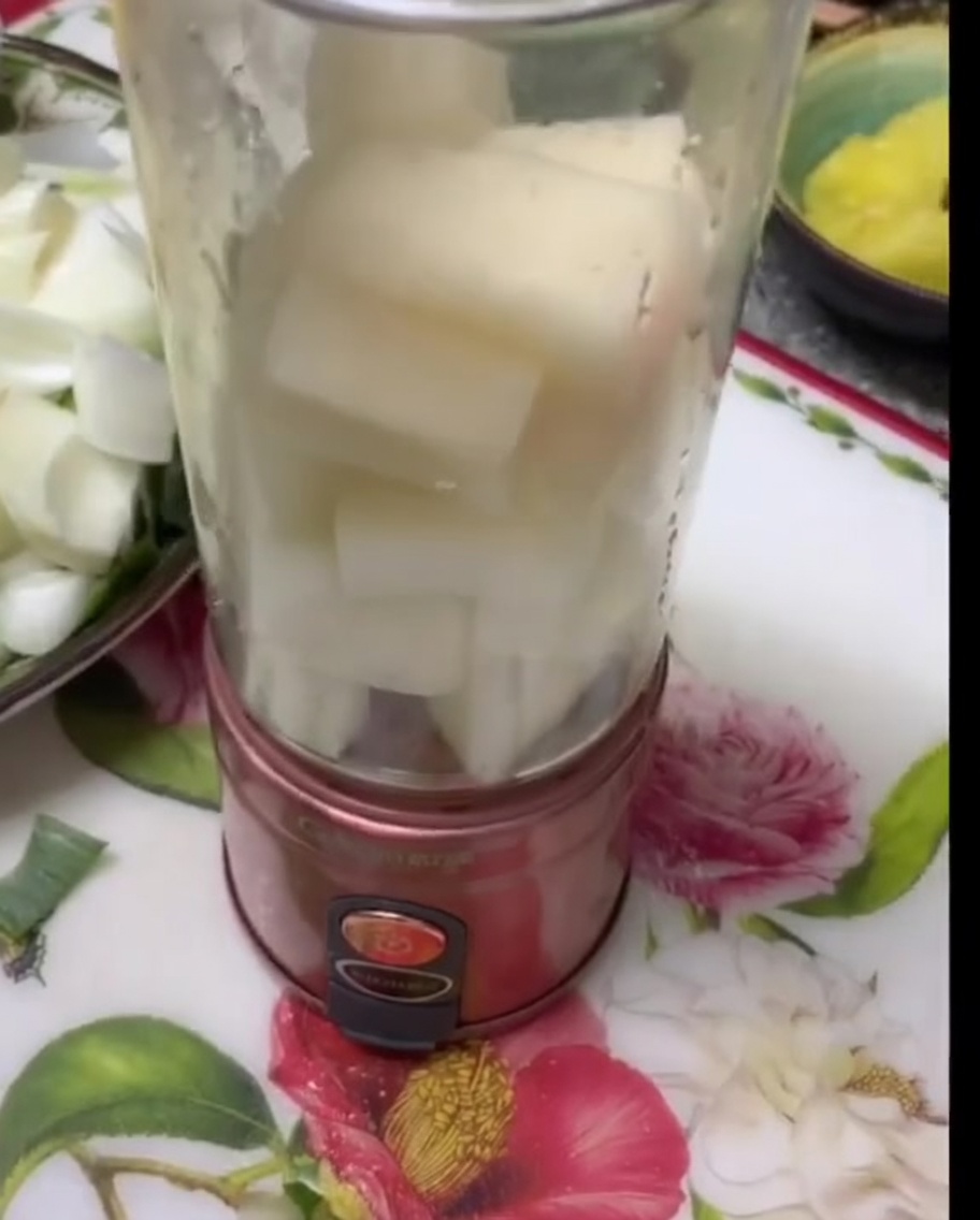 Morceaux de poire blanche et doignon empilés dans un bol de mixeur transparent.