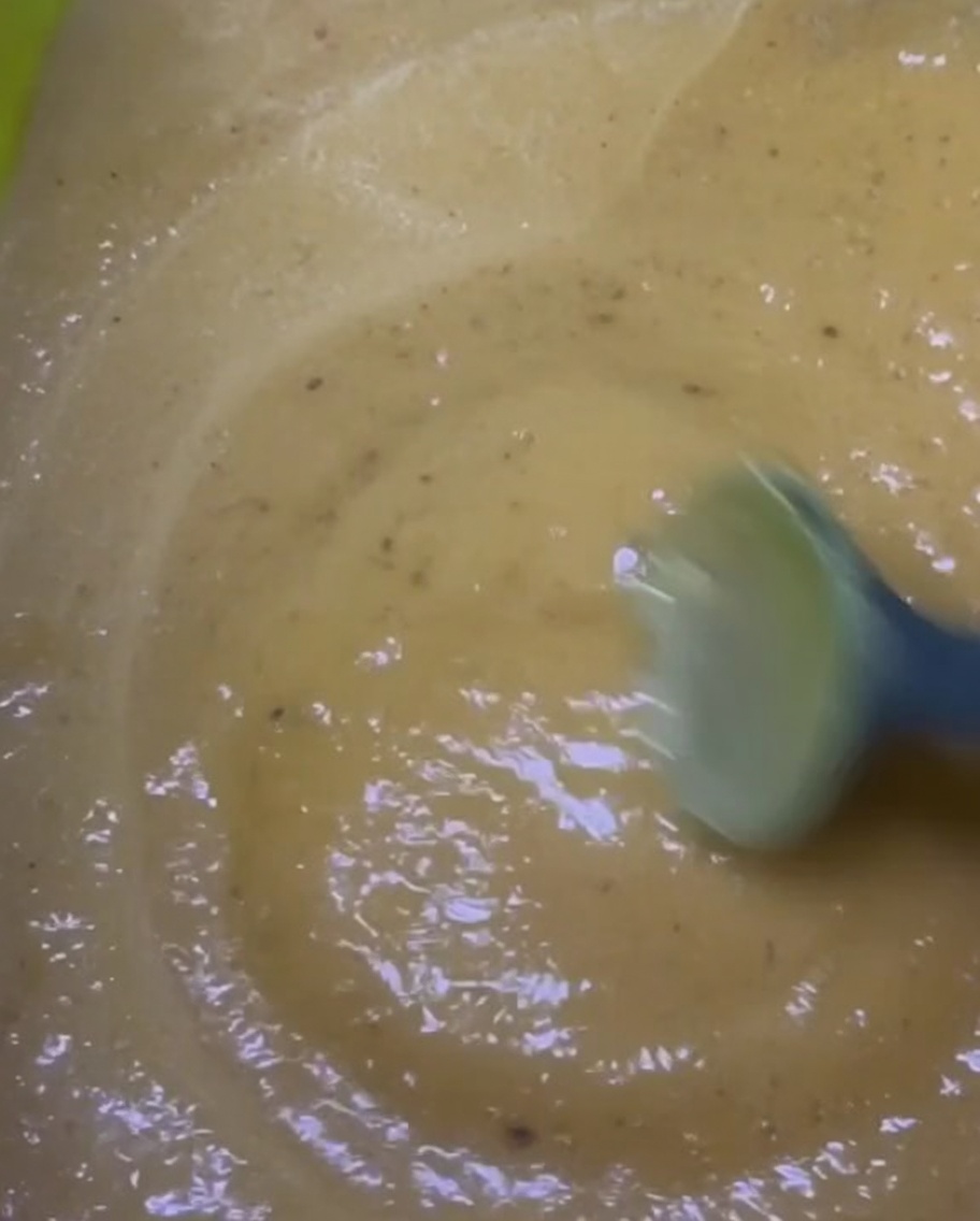 Mélange dune marinade épaisse jaune-brun dans un bol vert vif.