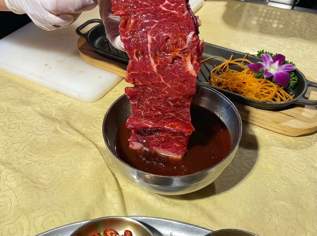 Une pièce de bœuf marinée soulevée dun bol, prête à être placée sur un plateau de service décoré.