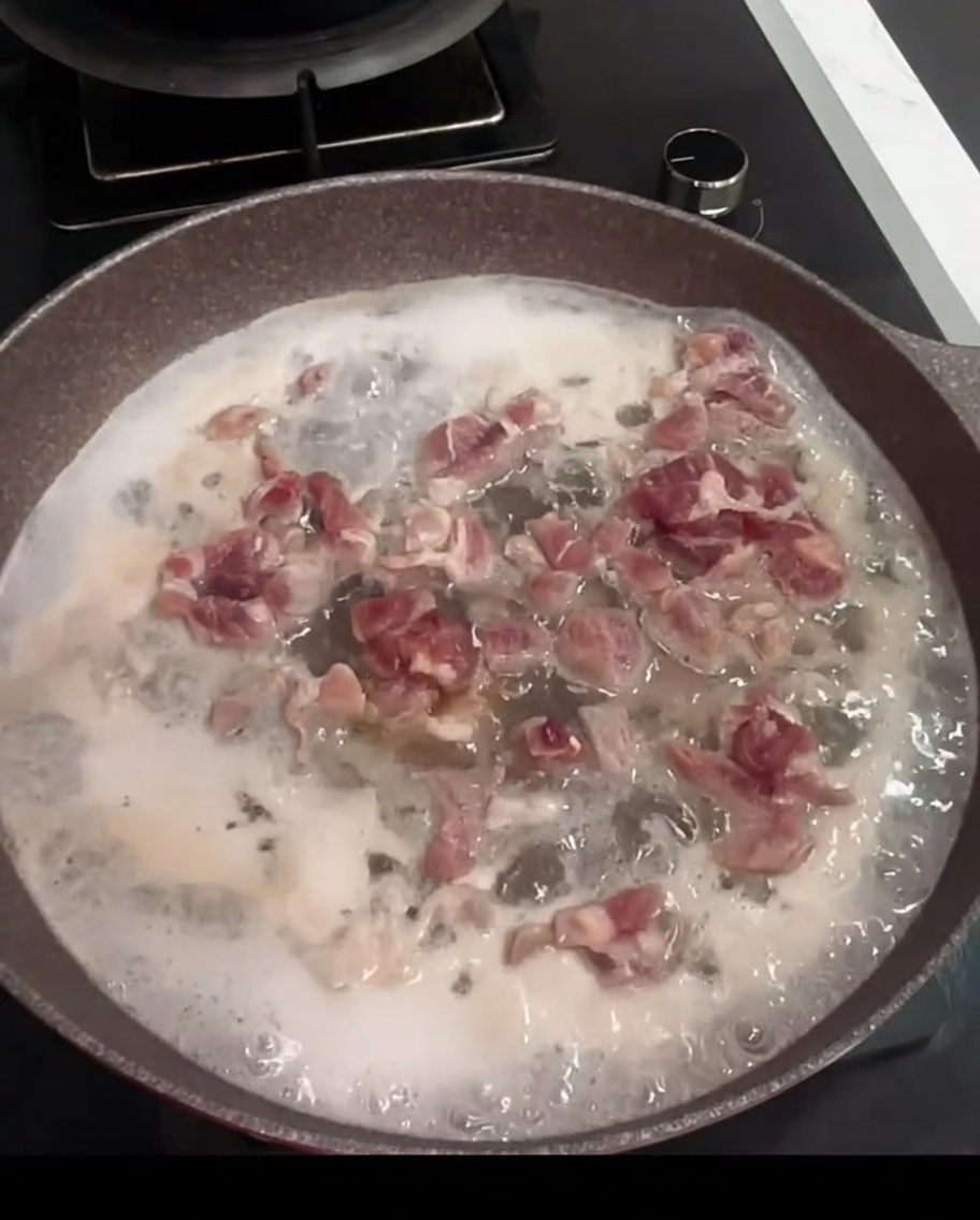 Morceaux de porc bouillant dans une casserole avec de leau, du vin de cuisine et une feuille de laurier.