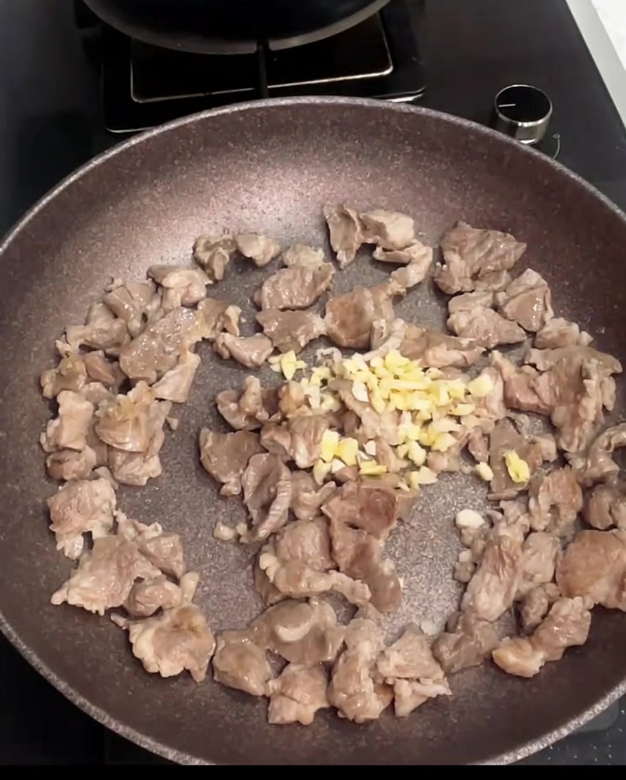 Morceaux de porc sautés dans une poêle avec de lail haché fraîchement ajouté.
