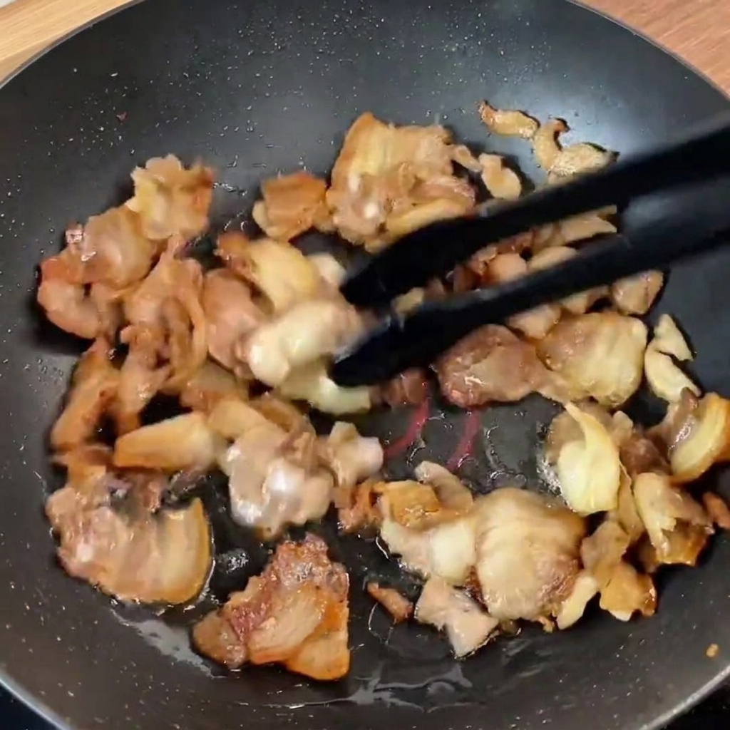 Lanières de poivron vert et lamelles doignon rouge ajoutées sur le porc saisi dans la poêle.