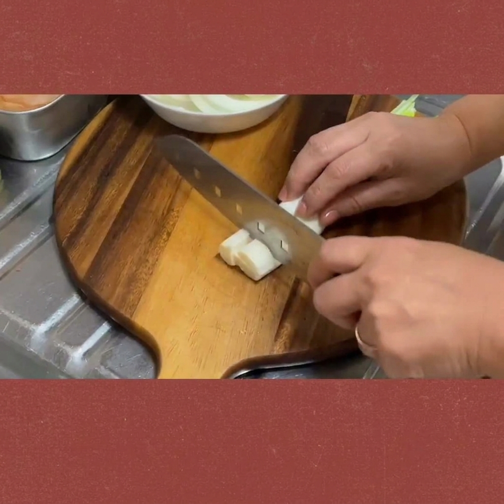 Des tiges doignons verts frais coupées en segments uniformes sur une planche.