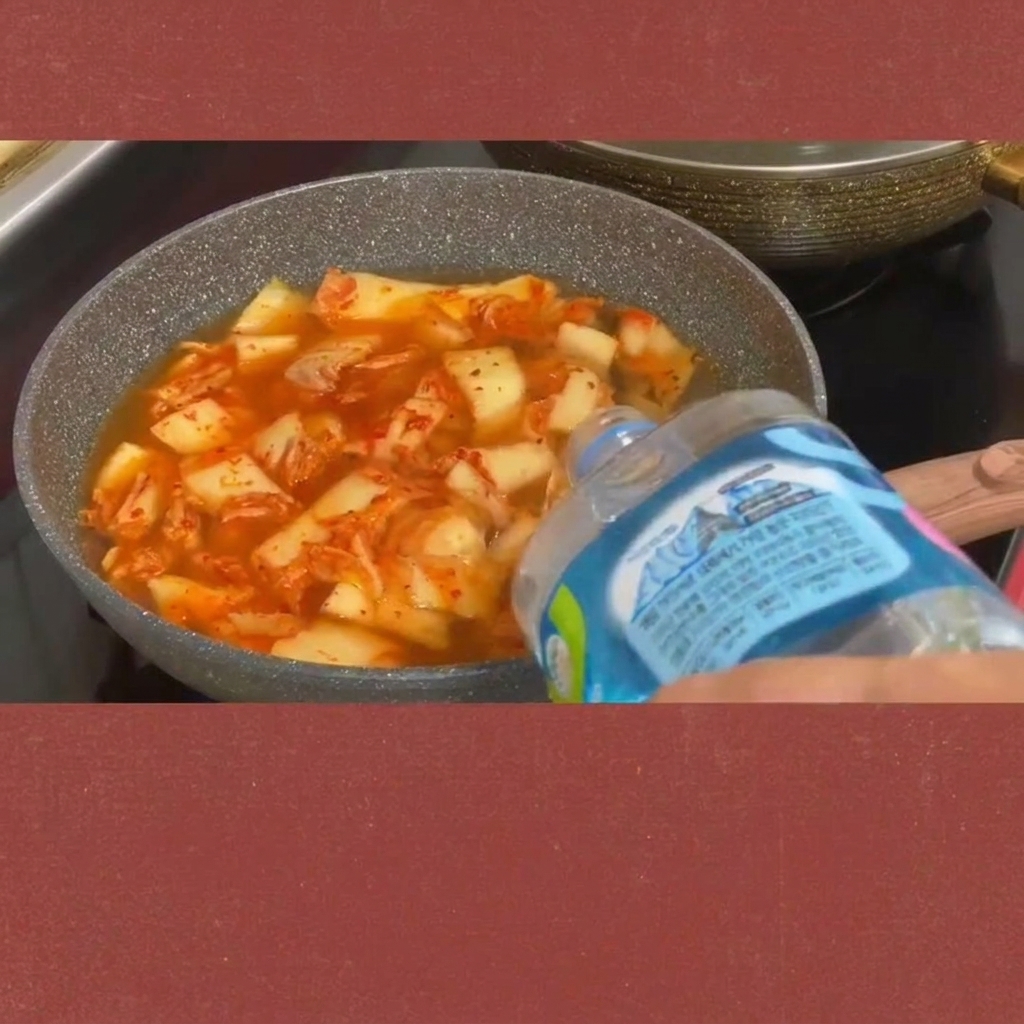 Des tranches de spam ajoutées dans le ragoût de kimchi bouillonnant.