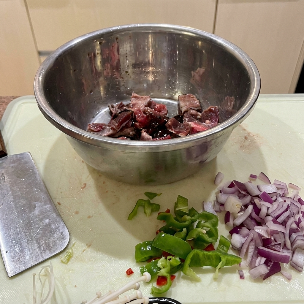 Morceaux de bœuf mariné dans un bol en inox avec la sauce soja, la sauce huître et la fécule.