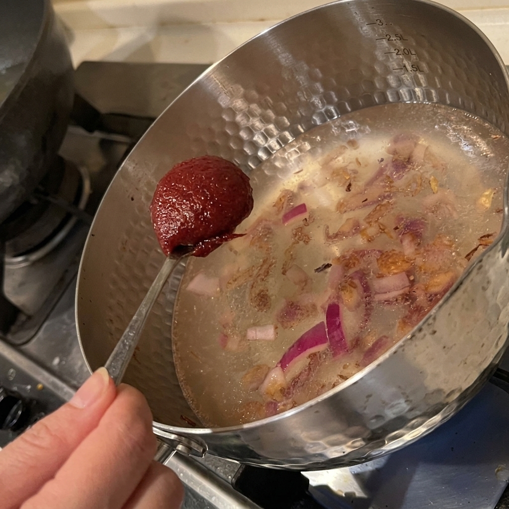 Ajout de pâte de piment coréenne dans la casserole avec les oignons.