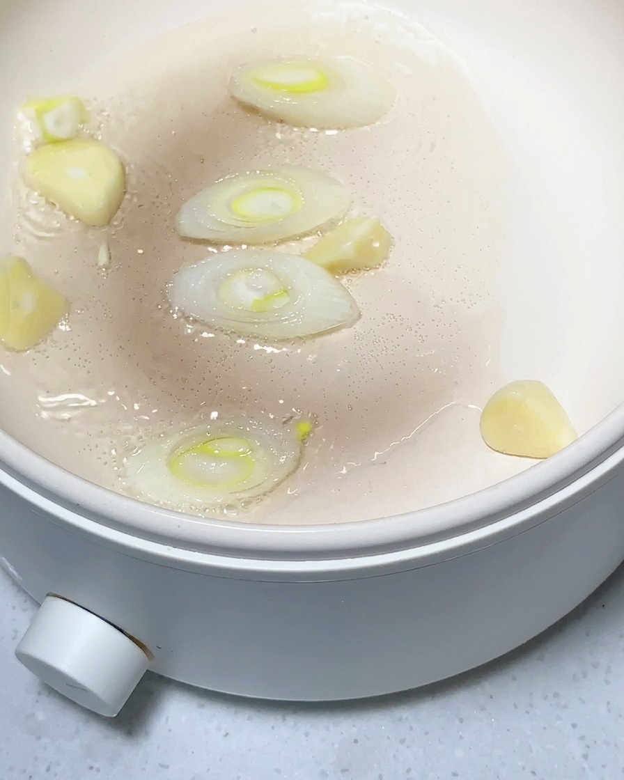Morceaux de pomme de terre, ail émincé et gingembre en train de revenir dans une poêle huilée.
