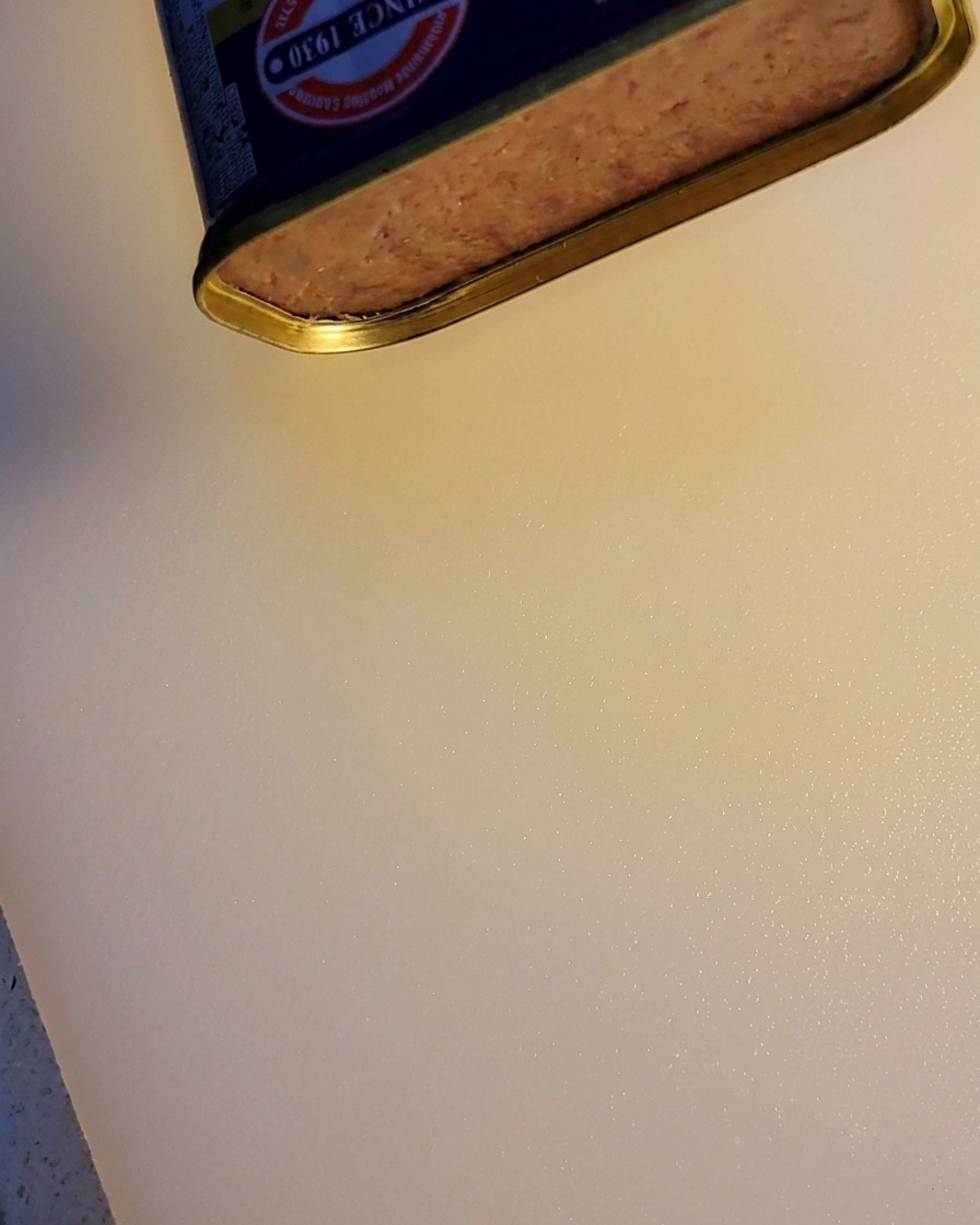 Un bloc de jambon en boîte en train dêtre tranché.