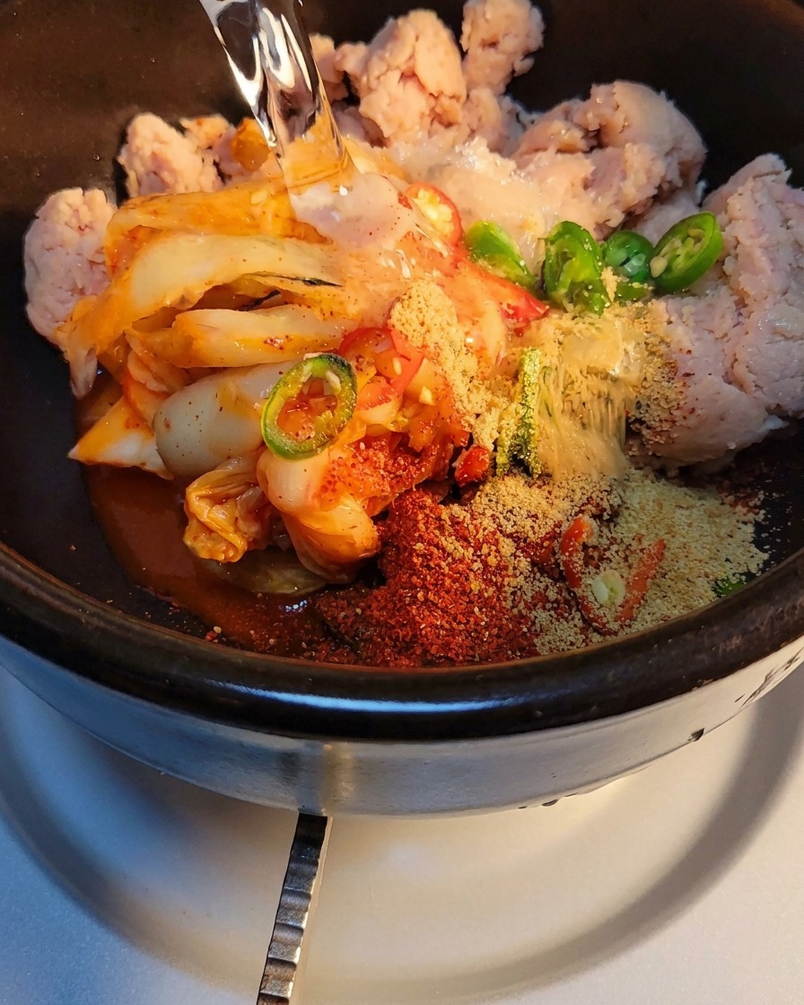 De leau versée dans le pot en pierre avec le kimchi et les épices.