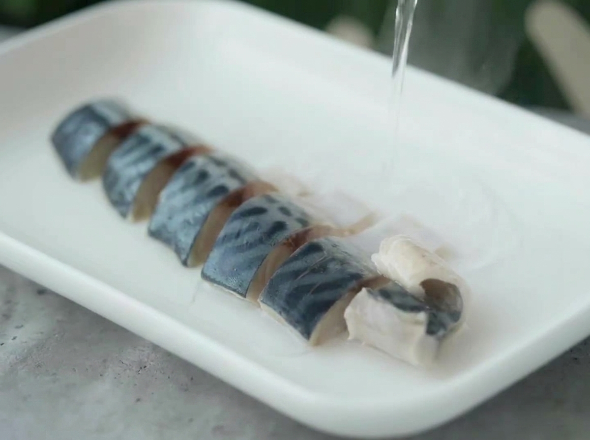 Eau chaude versée sur des morceaux de maquereau dans une assiette.