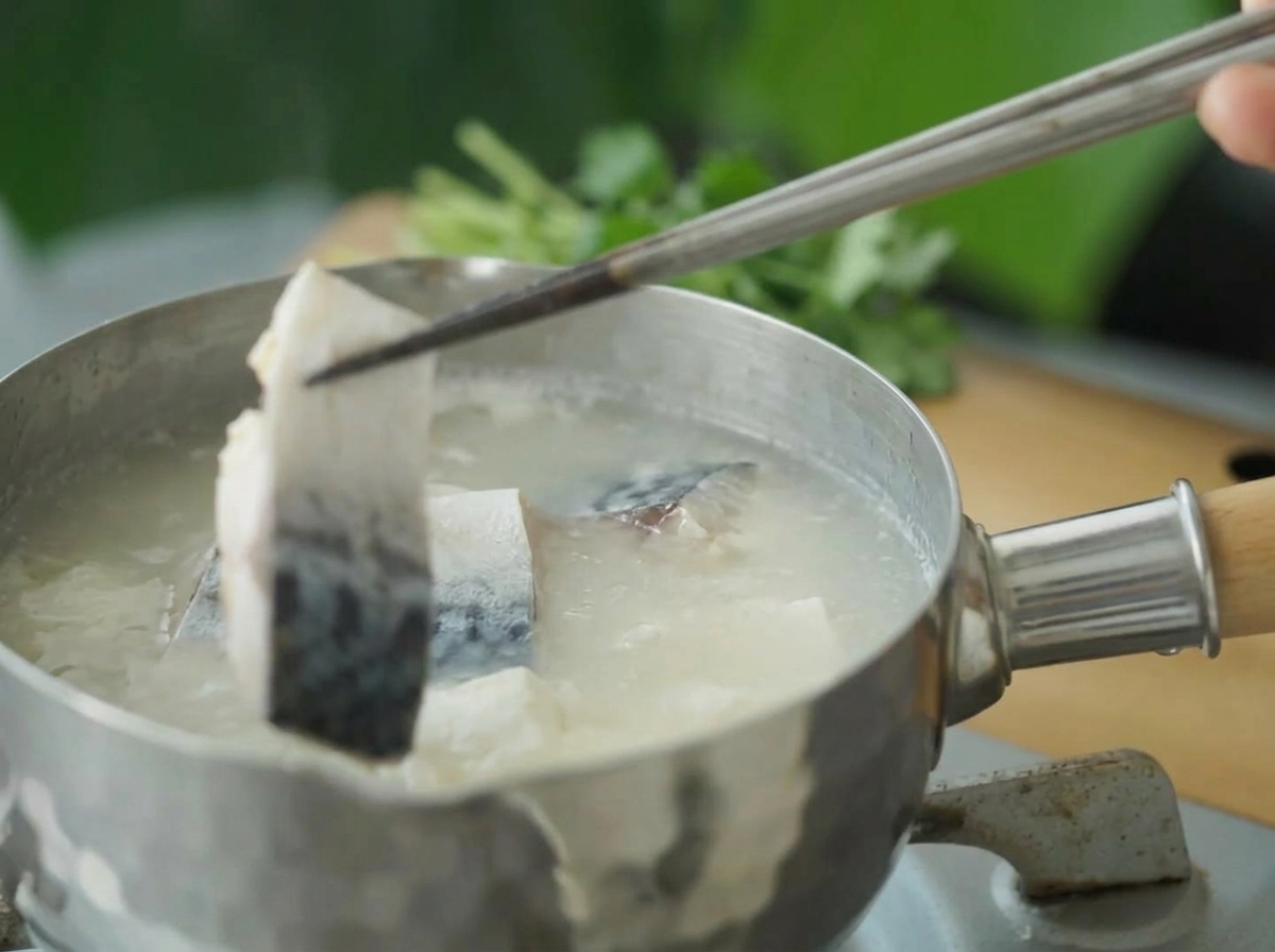 Morceaux de maquereau ajoutés avec des baguettes dans la soupe.