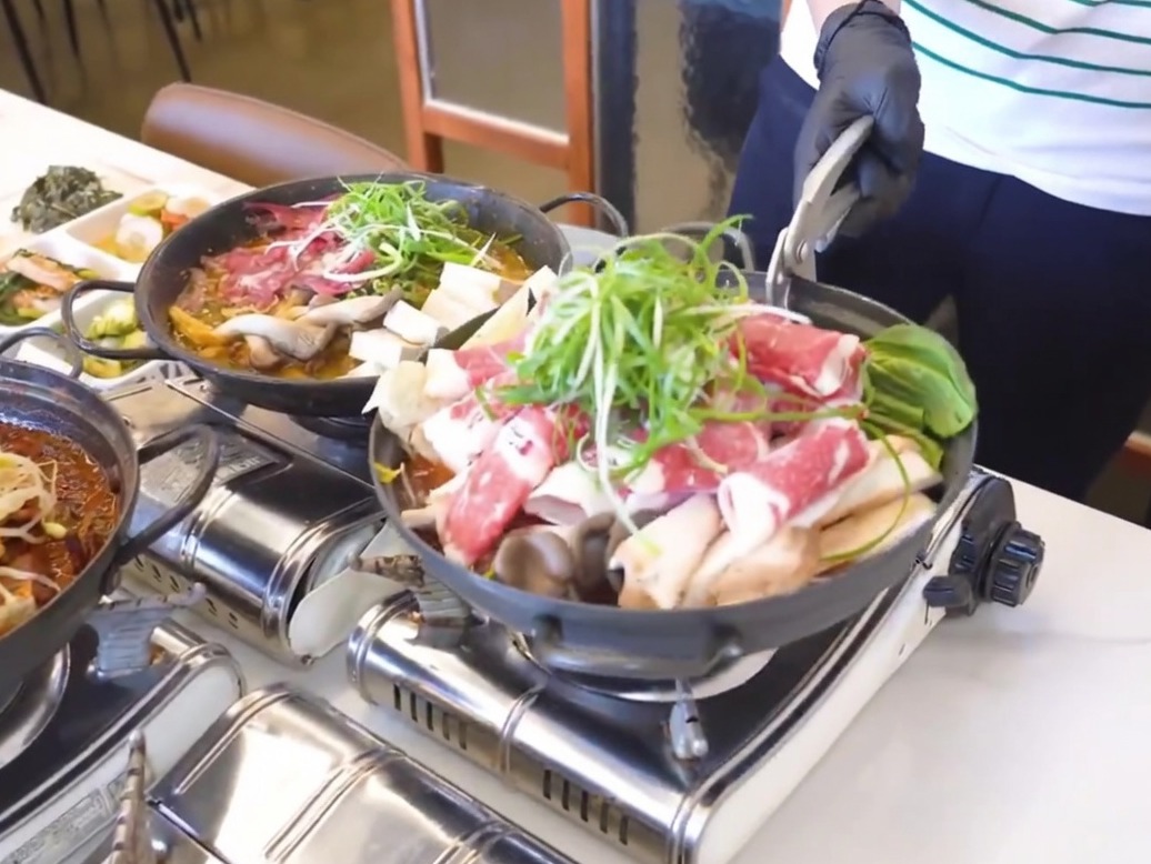 Une poêle en fonte noire préparée avec une couche de radis cuits et de kimchi au fond.