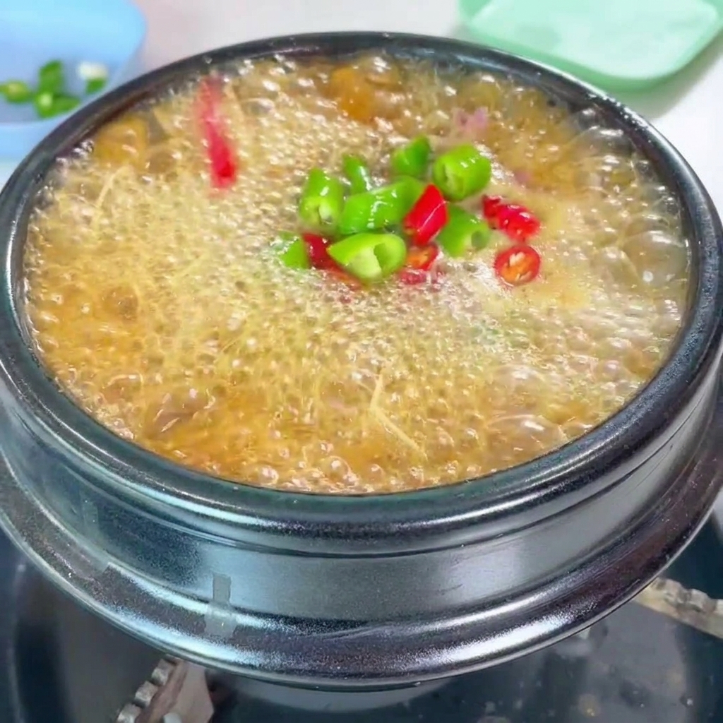 Une garniture vibrante de piments verts et rouges hachés et doignons verts frais ajoutée sur le ragoût.