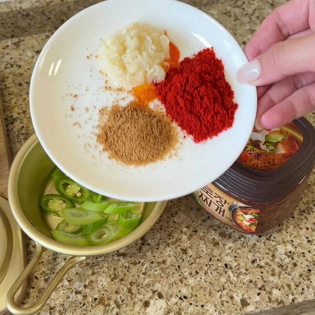 Assiette avec portions dail, piment, bouillon et poudre de perilla à côté du doenjang.