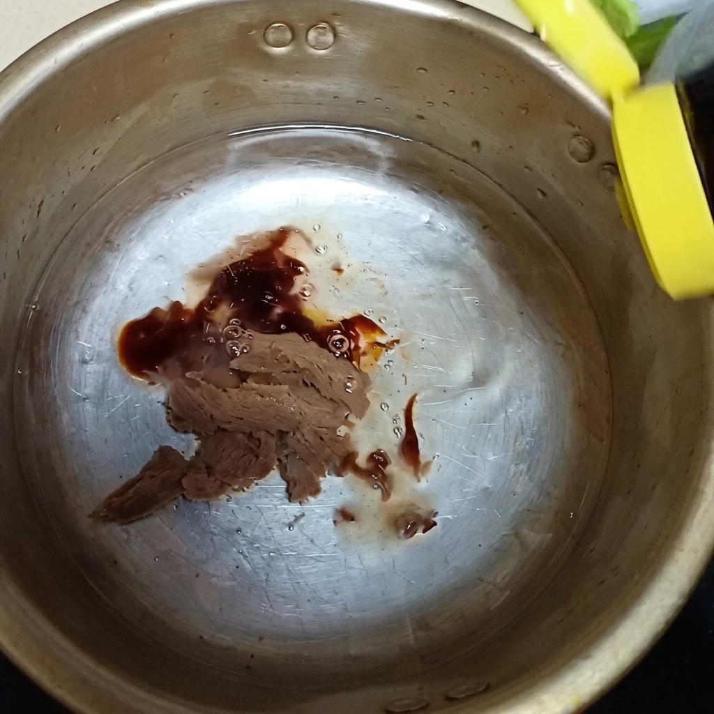 Sauce huître et un filet de sauce nuoc-mâm versés dans la casserole sur la pâte de soja.