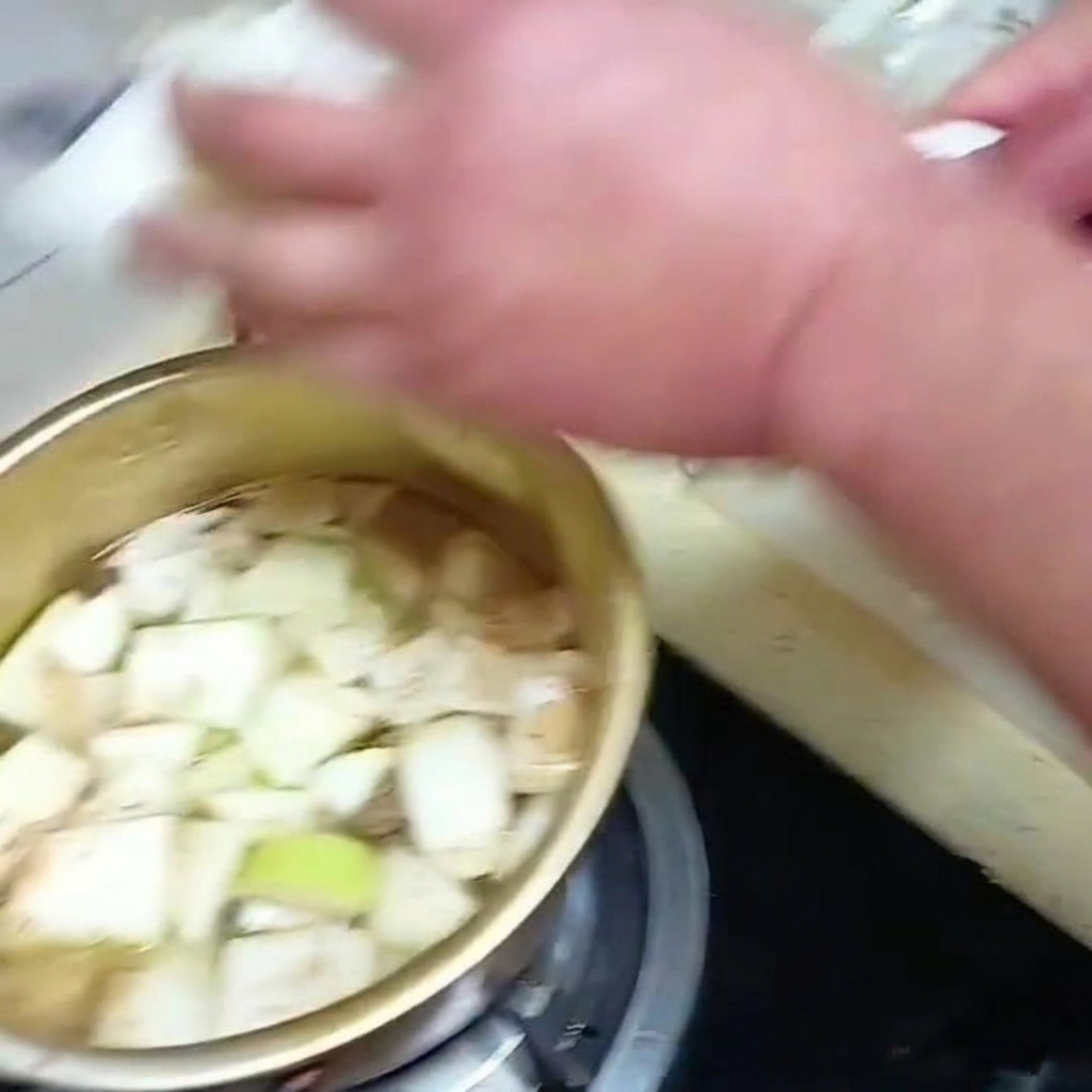 Feuilles de chou chinois tranchées placées dans une casserole de soupe frémissante avec les autres légumes.