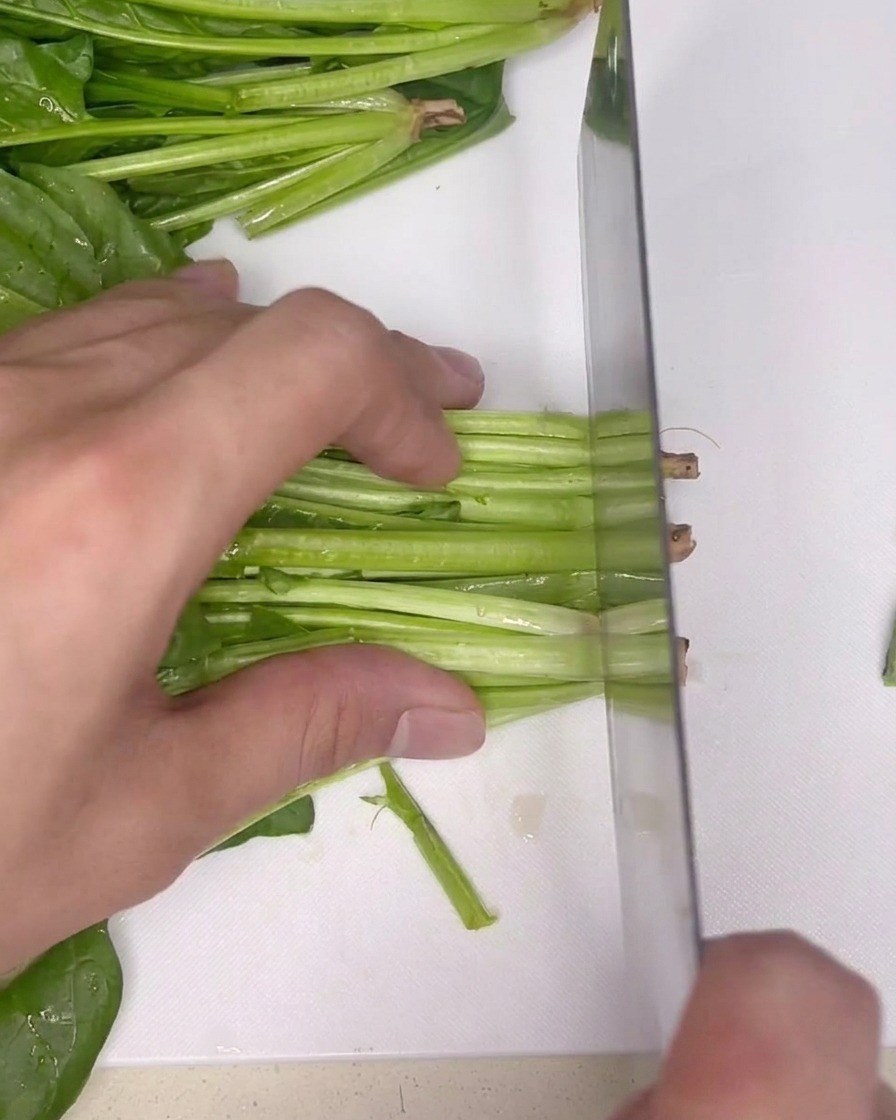 Bouquet dépinards frais sur une planche à découper, prêts à être parés au couteau.