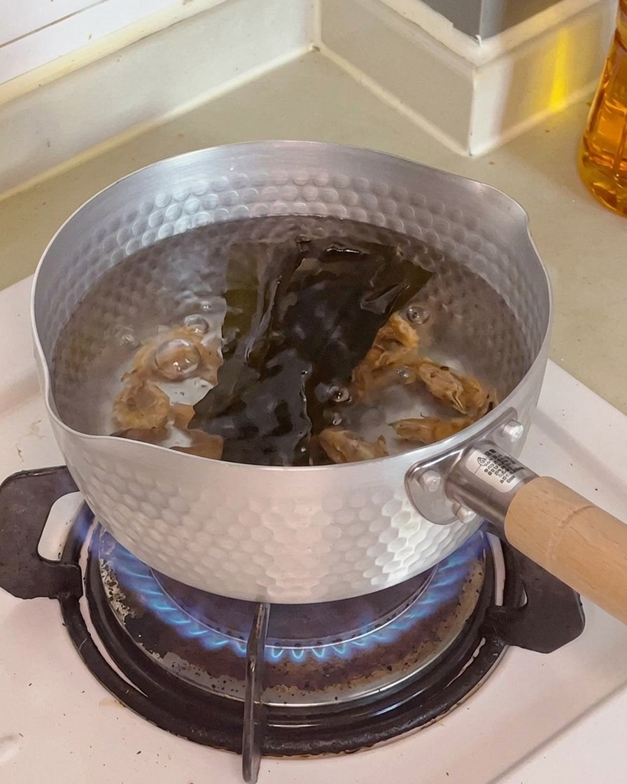 Gros plan sur des crevettes séchées et une algue kombu infusant dans leau chaude.