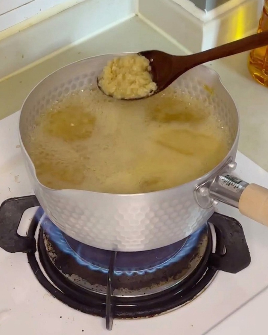 Cuillerée dail émincé ajoutée au bouillon frémissant.