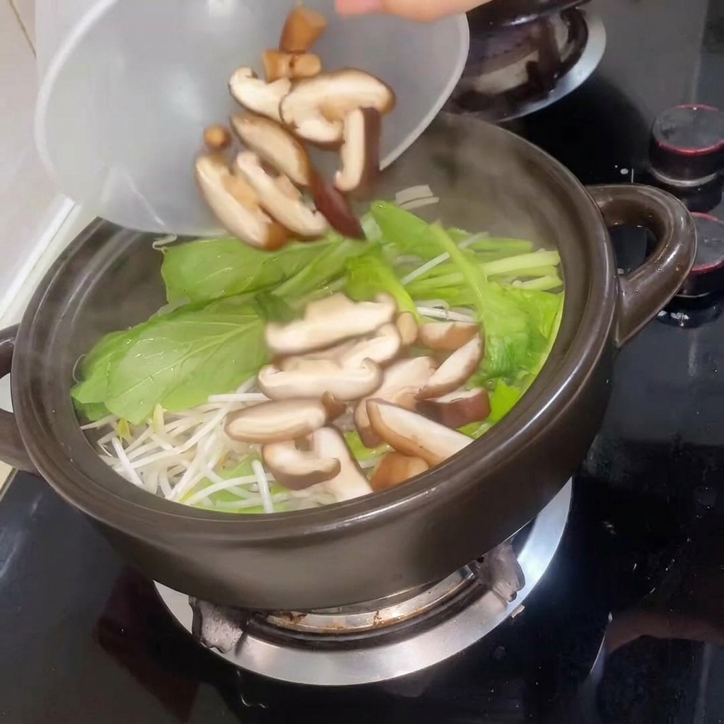 Champignons shiitake tranchés ajoutés à la marmite suivis deau chaude.
