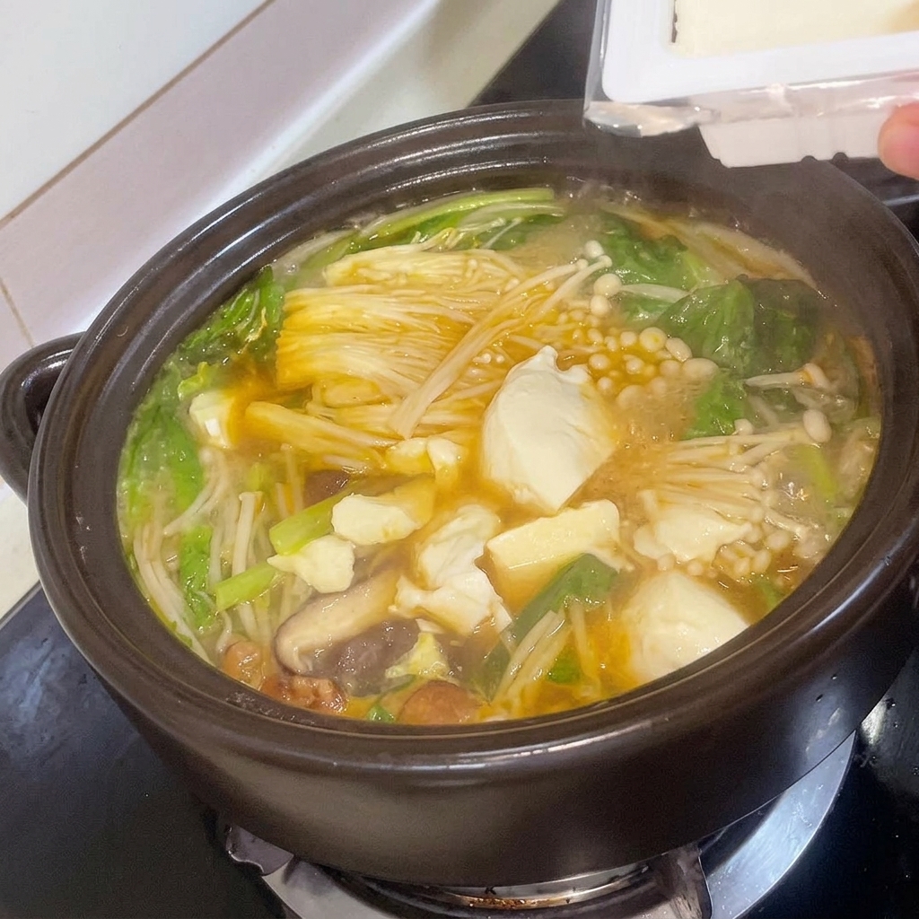 Dés de tofu frais ajoutés délicatement au ragoût de soja coréen mijotant.