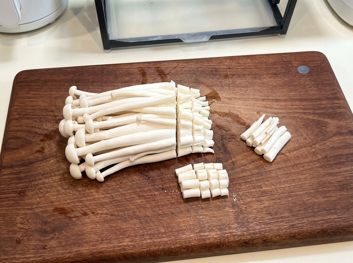 Champignons de mer frais sur une planche à découper en bois, dont les pieds sont coupés au couteau.