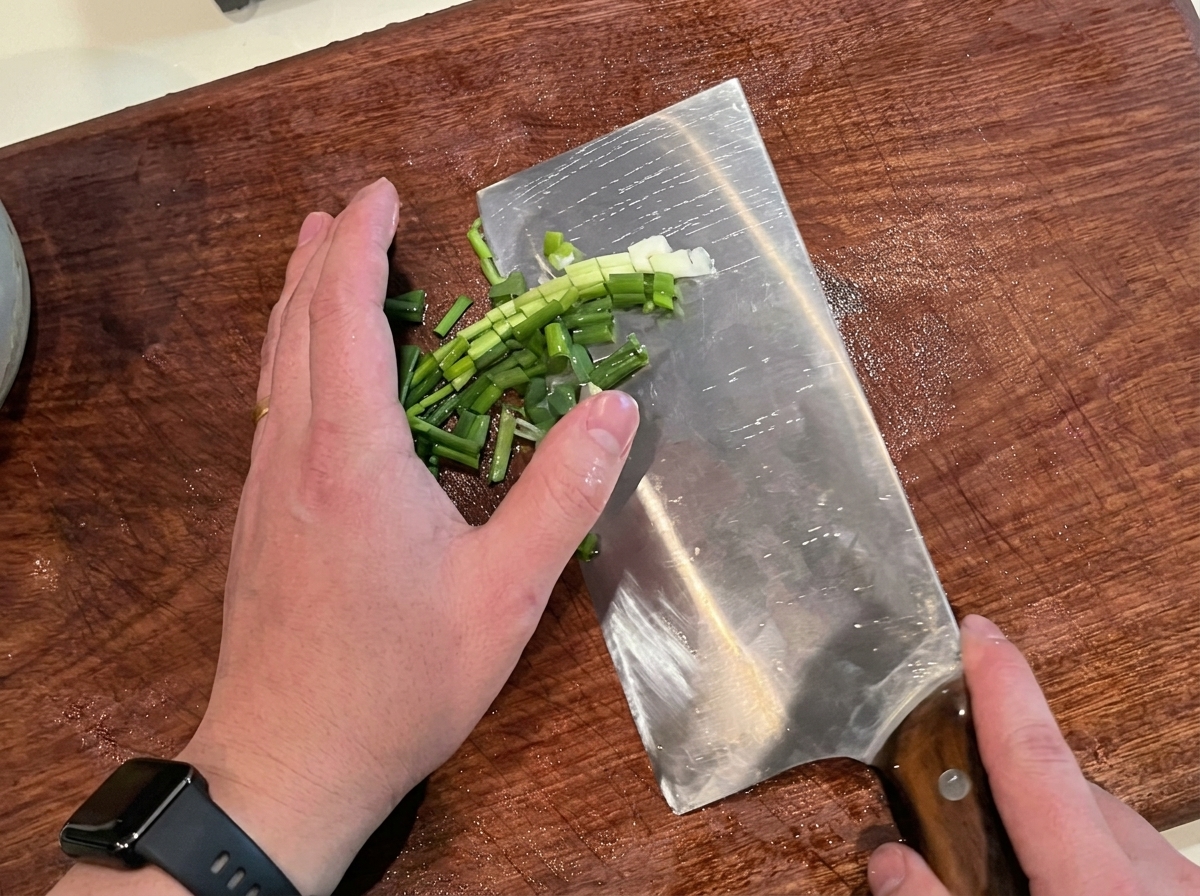 Cébettes fraîches finement ciselées sur une planche à découper.