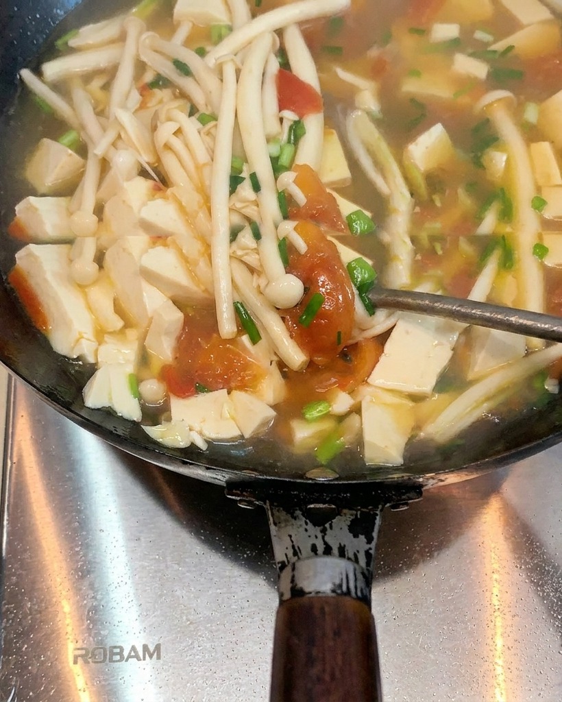Tomates cuisant dans un wok avec le saindoux, commençant à ramollir.