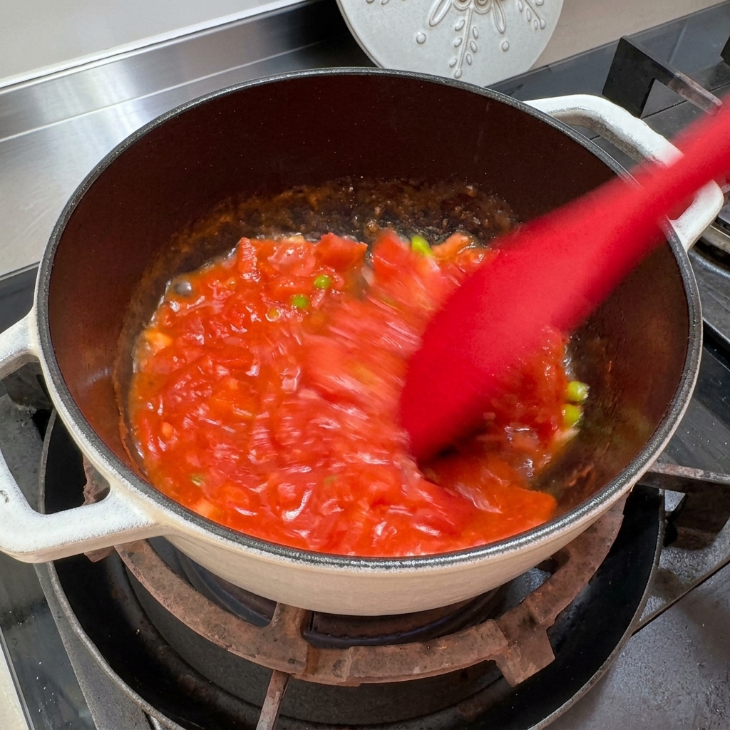 Tomates écrasées et mélangées dans une casserole pour créer une consistance de sauce.