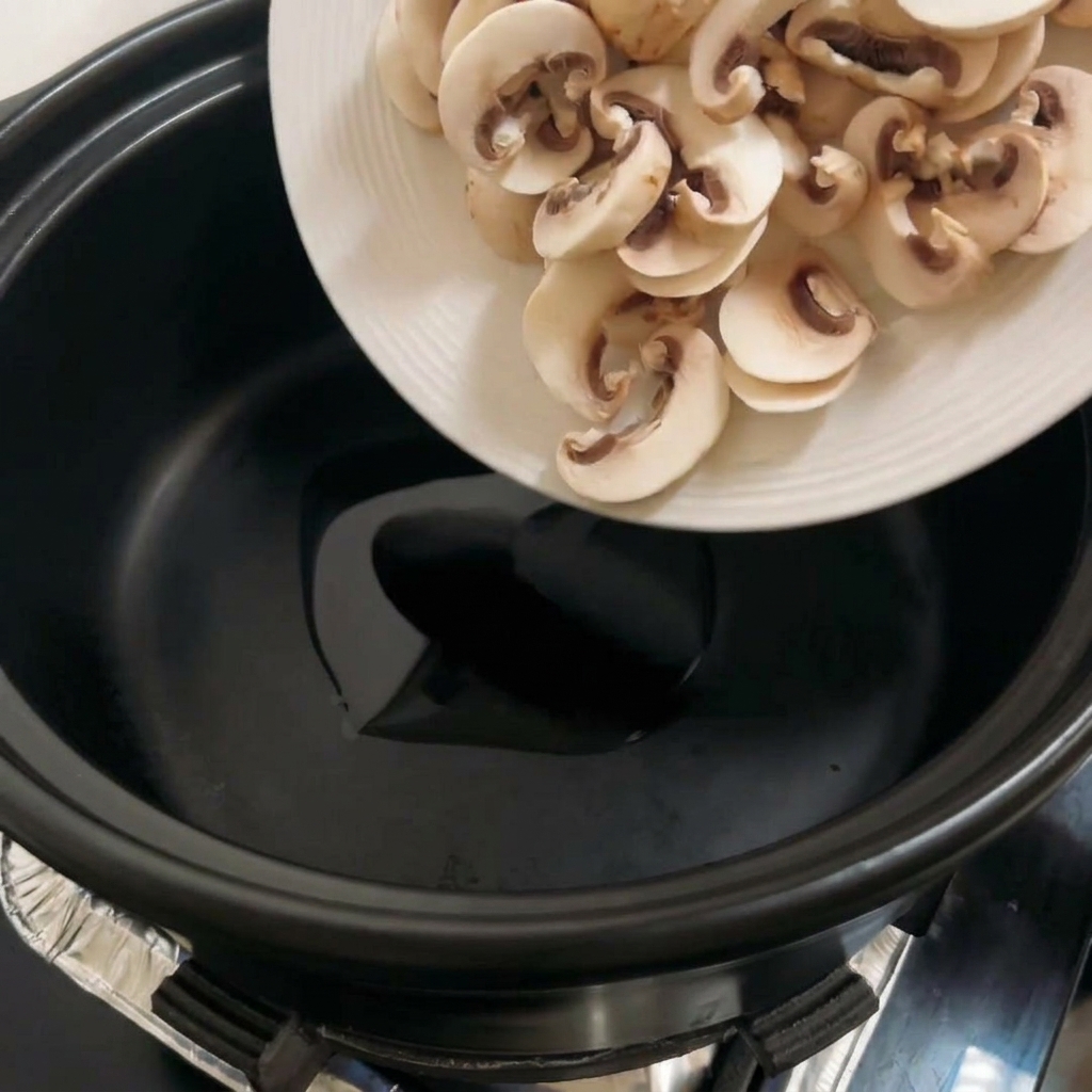 Champignons portobello tranchés cuisant dans une casserole noire, devenant dorés.