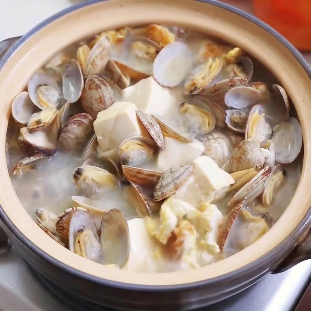 Gros plan sur la poudre de poulet, le sel et le poivre saupoudrés dans la soupe bouillonnante.