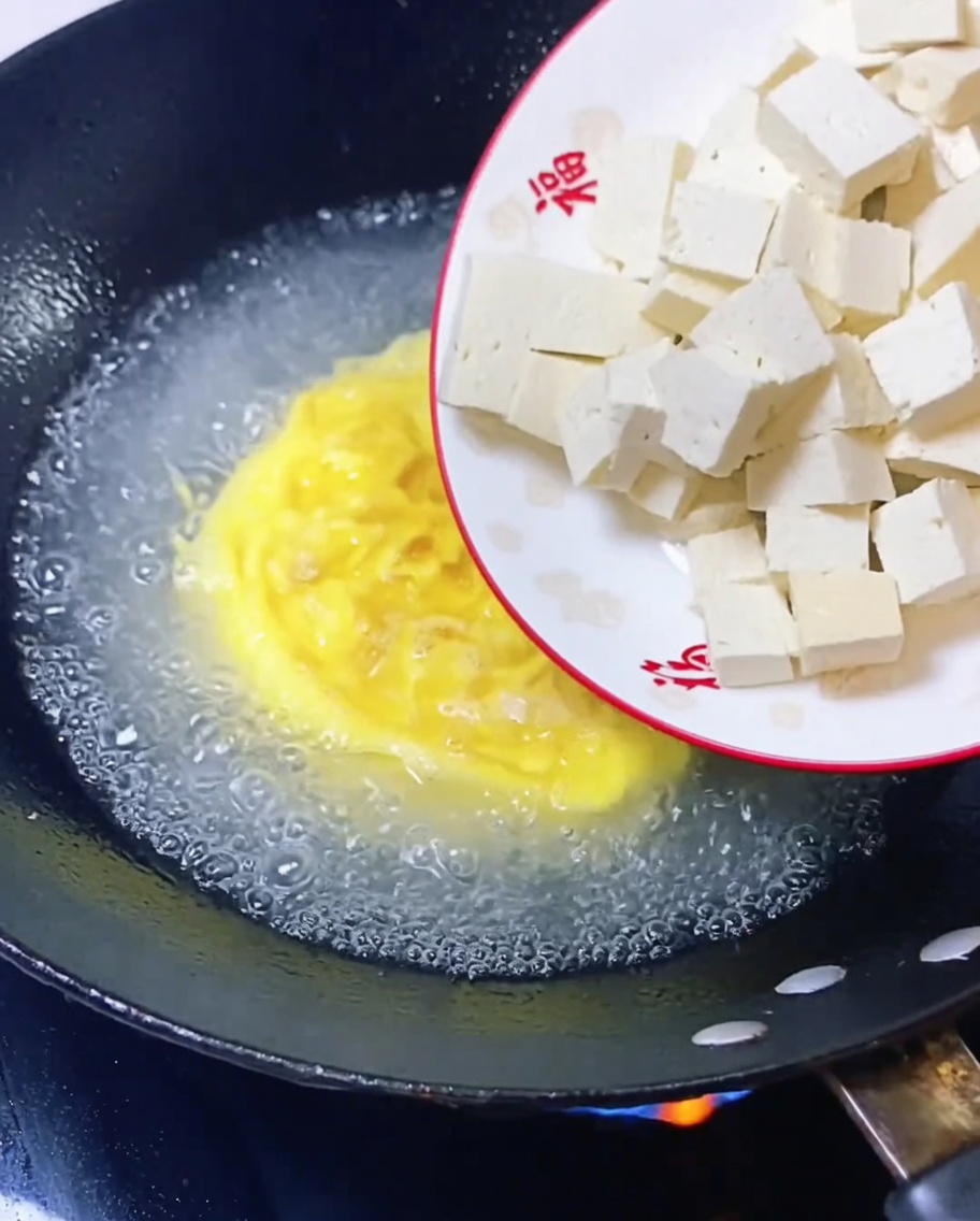 Cubes de tofu ajoutés au bouillon frémissant.