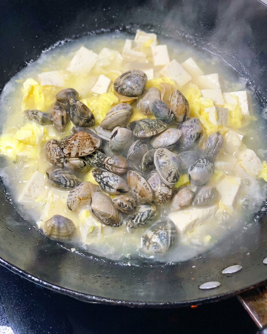 Palourdes fraîches ajoutées dans le wok avec le tofu et les œufs.
