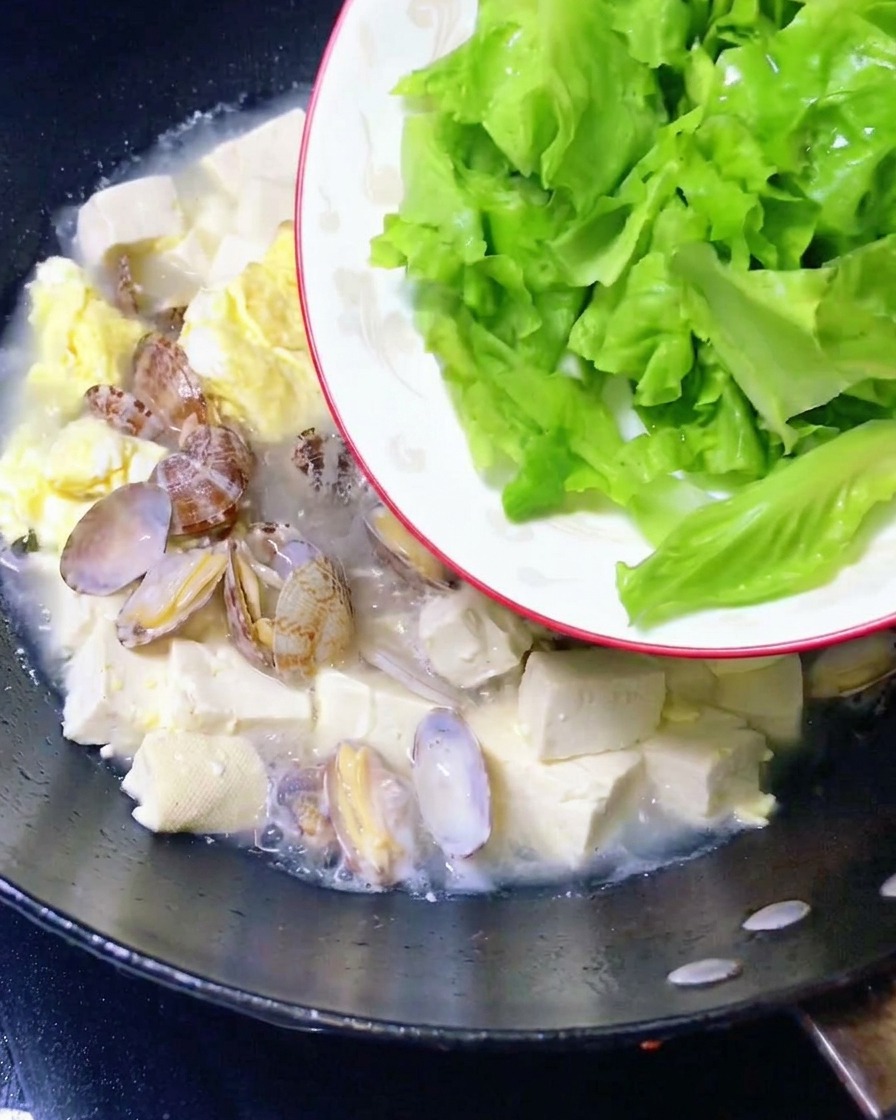 Feuilles de laitue intégrées à la soupe de palourdes et de tofu.
