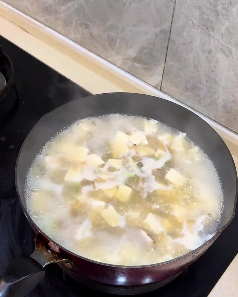 Oignons verts hachés ajoutés à la soupe de palourdes et tofu terminée.