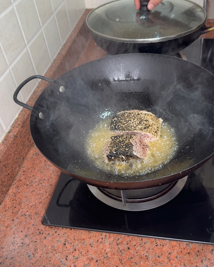 Morceaux de mérou assaisonnés saisissant dans de lhuile bouillonnante dans un wok.