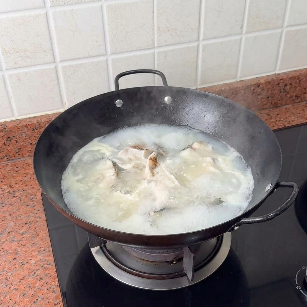 Dés de tofu déposés délicatement dans le bouillon de poisson bouillant et crémeux.