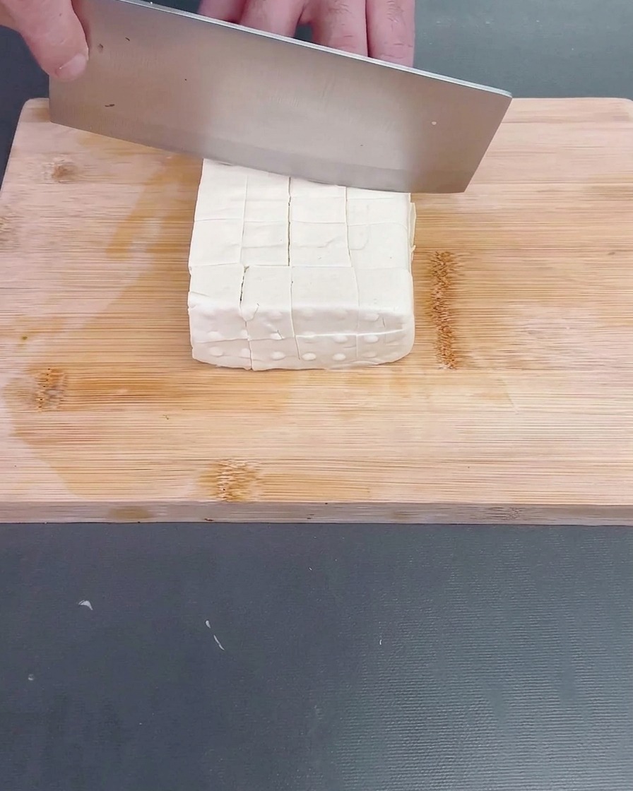 Un luffa épluché en train dêtre coupé en tronçons irréguliers.