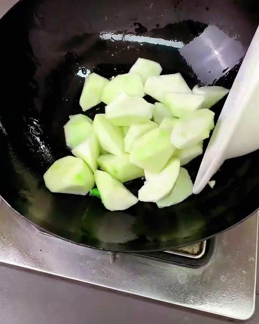 Morceaux de luffa sautés dans le wok avec les aromates.