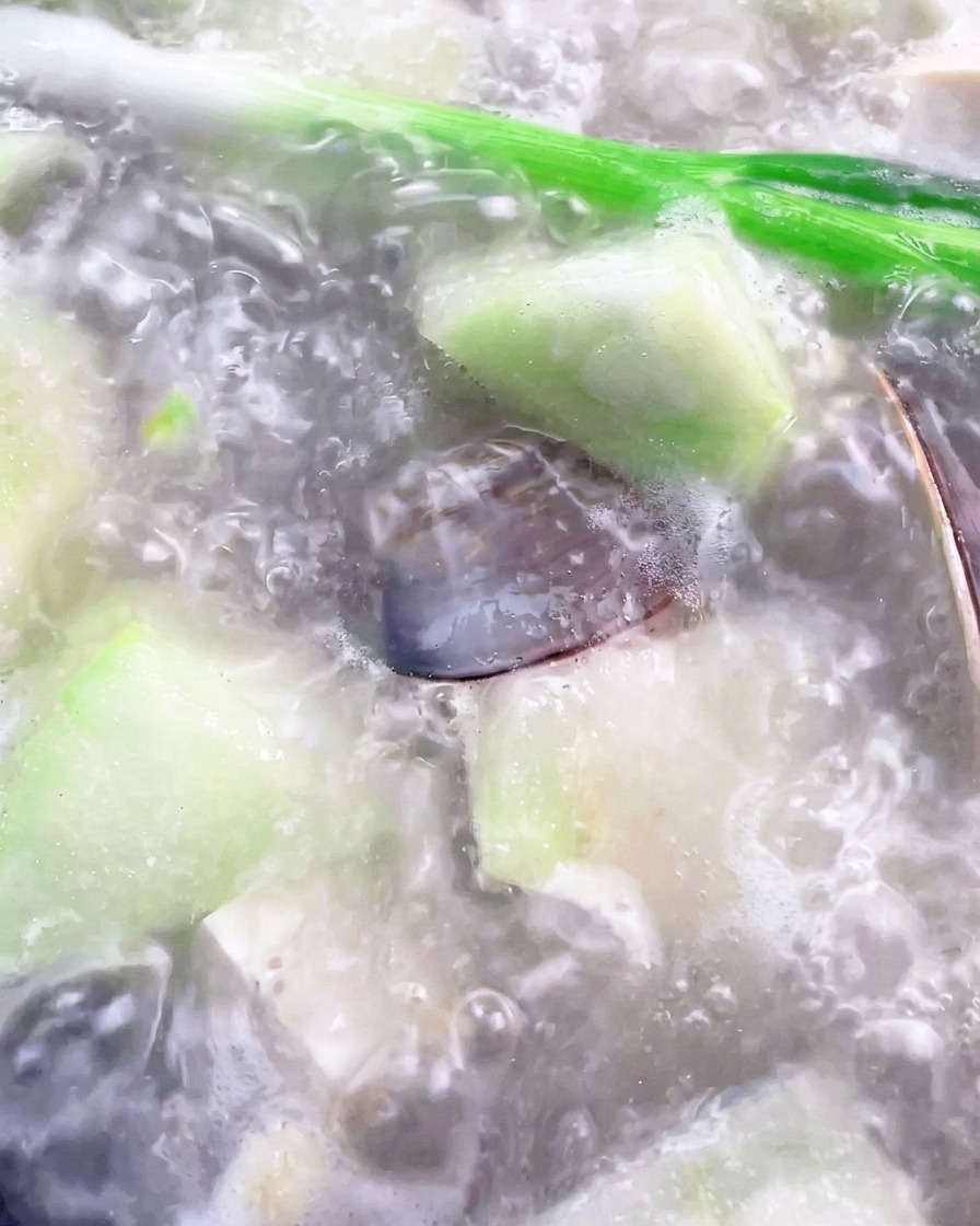 Une louche retirant la mousse de la surface du bouillon bouillant.