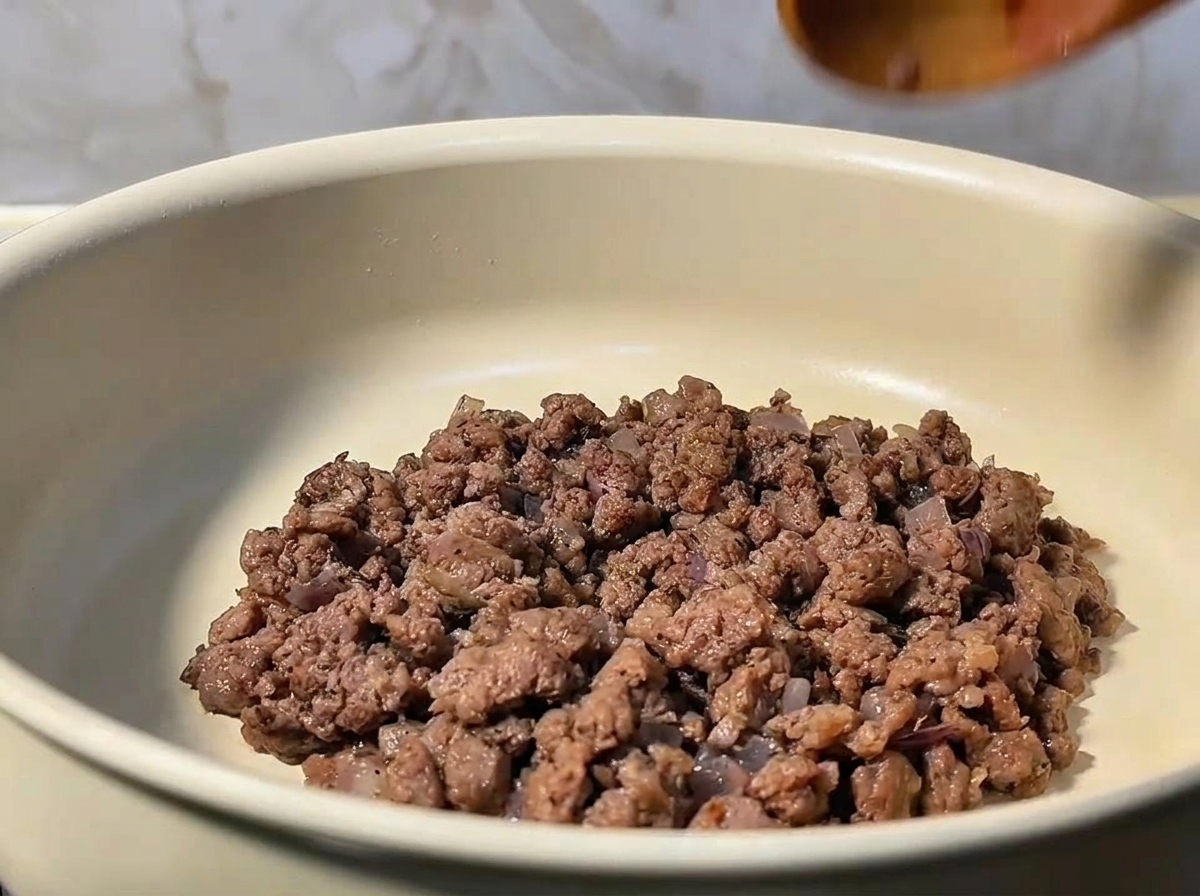 Du bœuf haché étant mélangé et émietté dans une poêle avec des oignons.