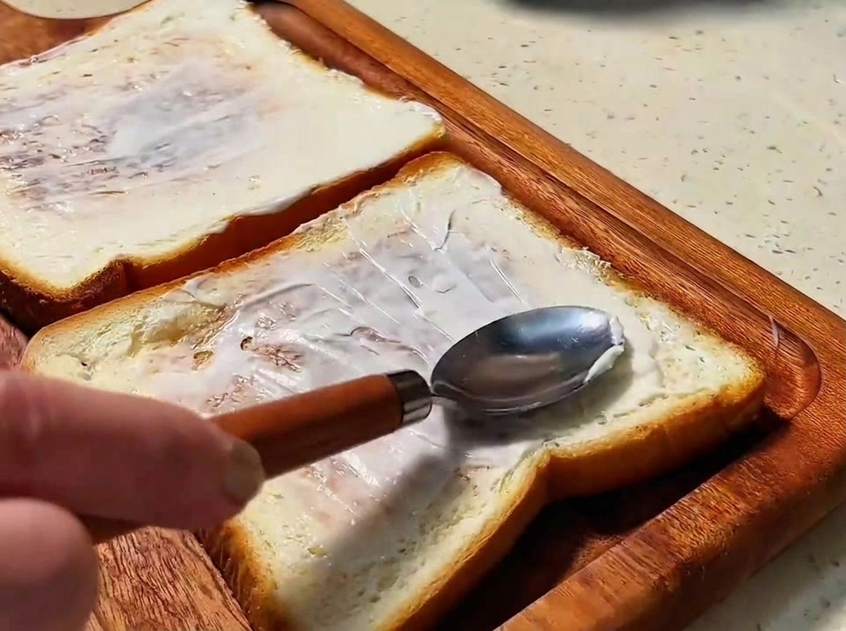 Deux tranches de pain doré tartinées dune couche lisse de mayonnaise.