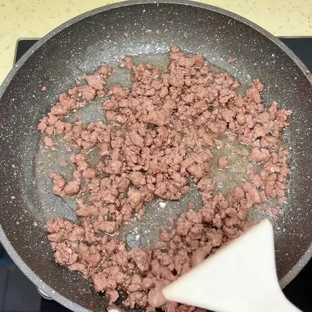 Une poêle contenant du bœuf et des oignons cuits