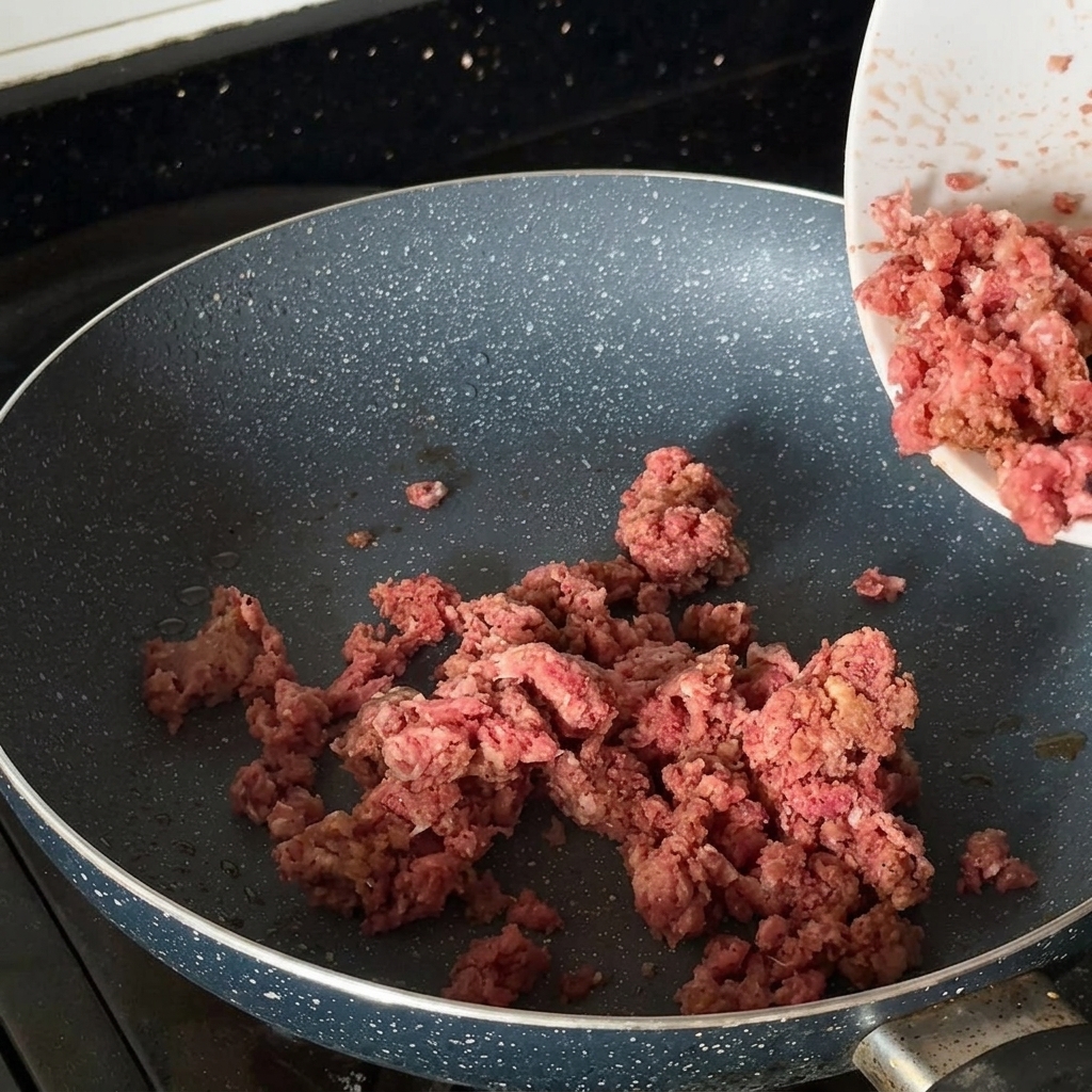 Bœuf haché assaisonné en train de dorer dans une poêle chaude.