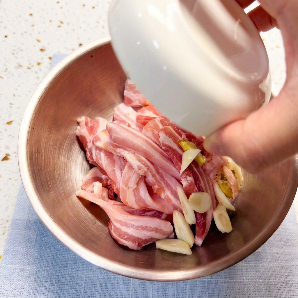 Tranches de poitrine de porc marinées dans un bol en métal avec divers assaisonnements.