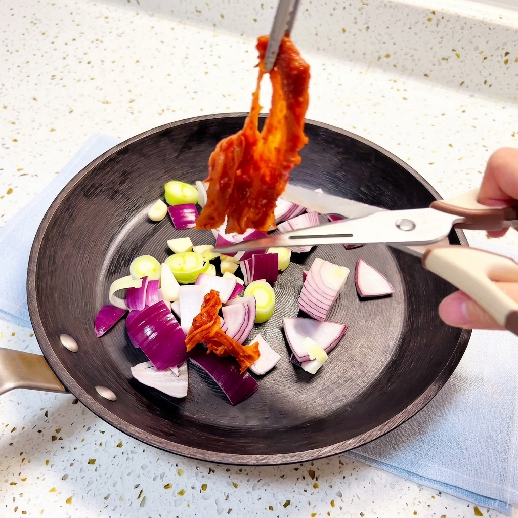 Kimchi coupé avec des ciseaux de cuisine directement dans la poêle contenant les aromates.