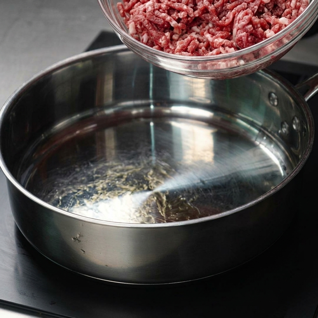 Bœuf haché transféré dun bol en verre dans une poêle chaude.