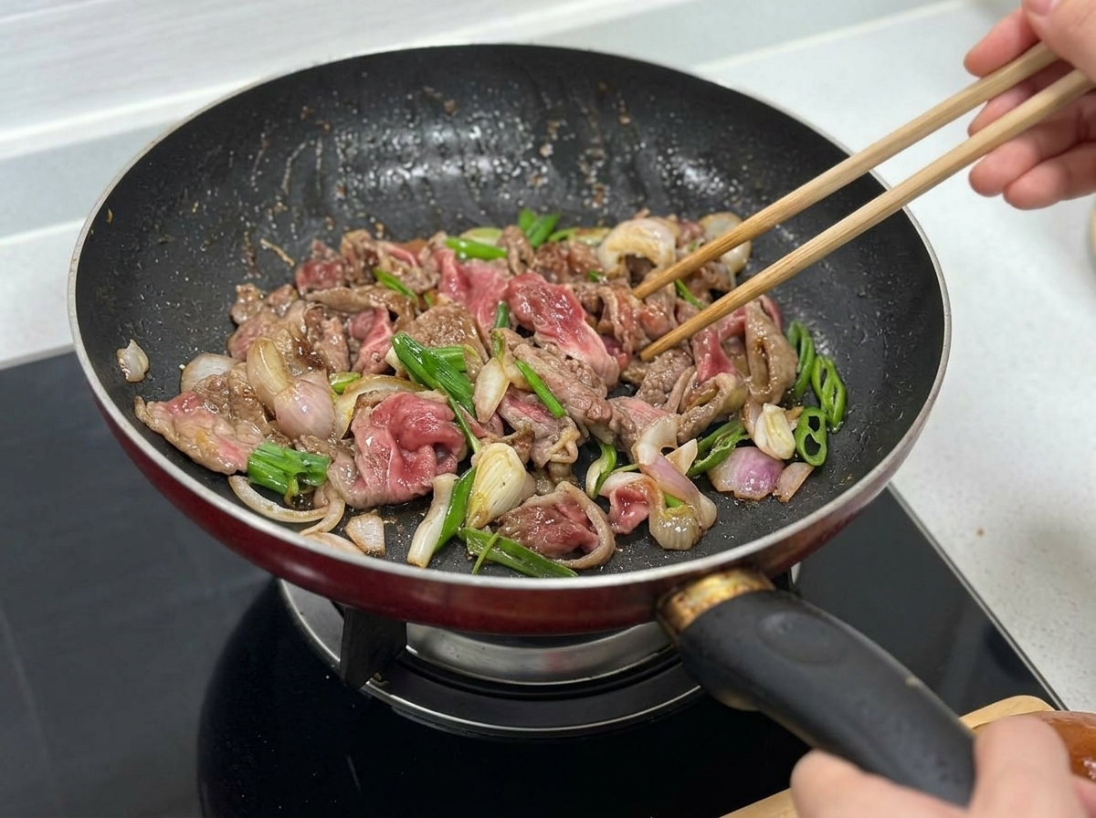 Bœuf, oignons et poivrons verts sautant ensemble dans la poêle.