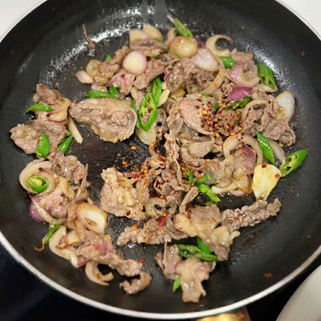 Assaisonnements saupoudrés sur le bœuf, les oignons et les poivrons dans la poêle.